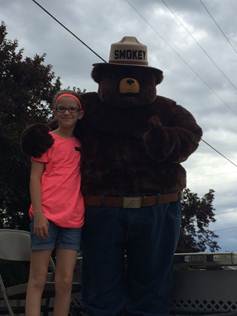 A girl with pink shirt and the smokey bear