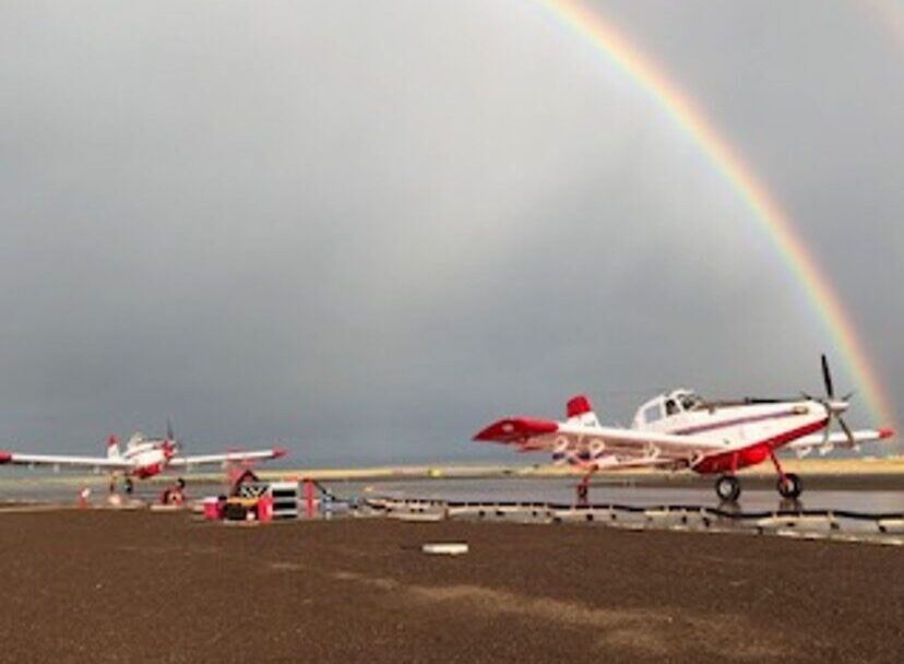 Two air tankers at the airport with a rainbow in the background